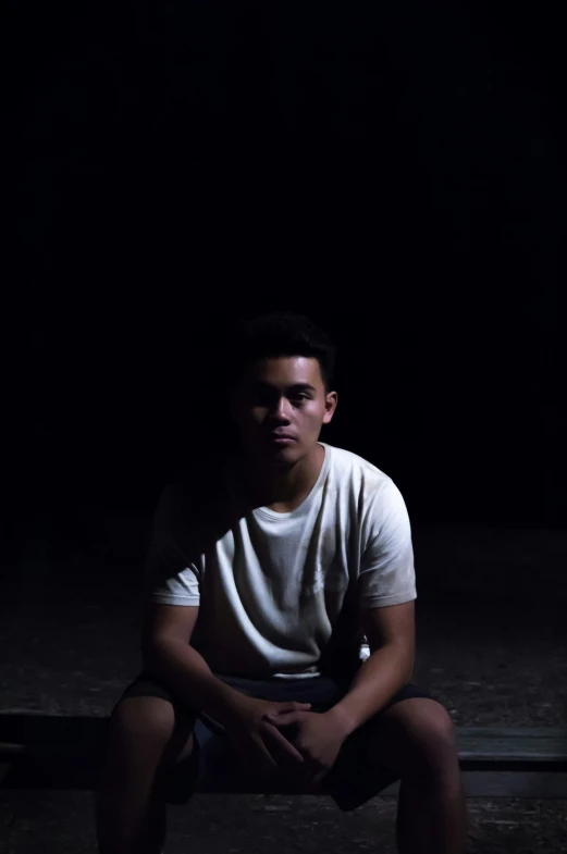 a young man sitting in the dark in his underwear