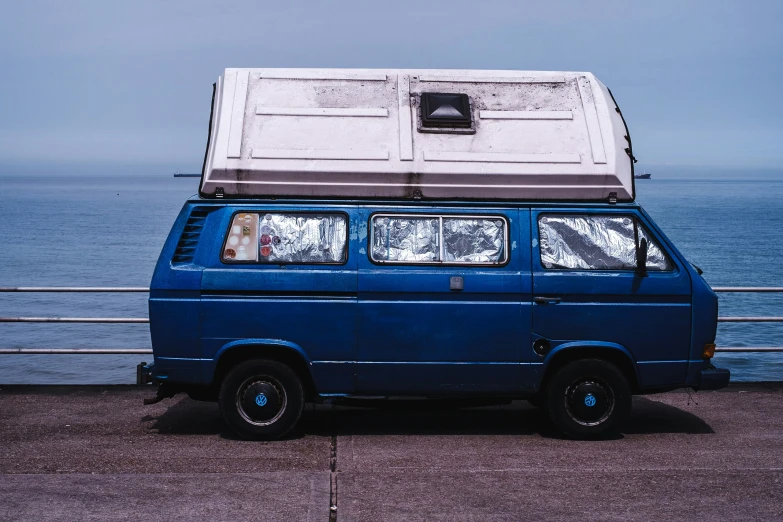 the small van is parked next to the ocean