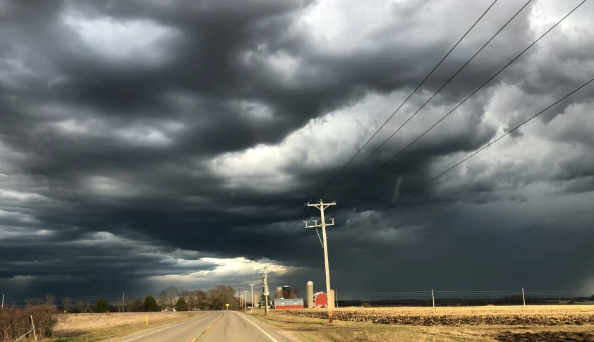 dark clouds loom over an open field as an intersection