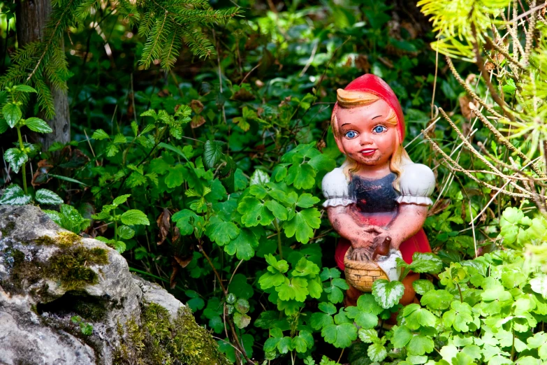 a statue of a little red riding hood sitting on top of a rock in the forest