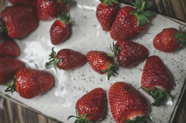 fresh strawberries sit on a plate in the sun