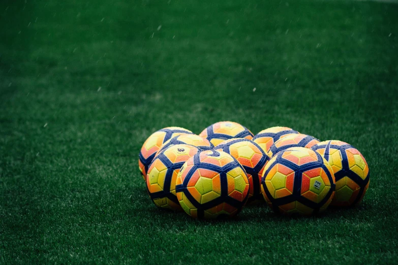 two large soccer balls on top of a green field