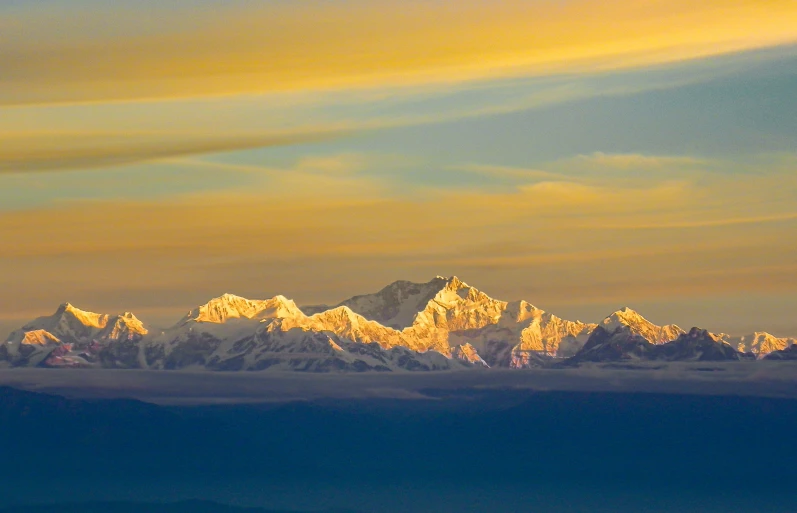 the snow covered mountains rise above clouds at sunrise