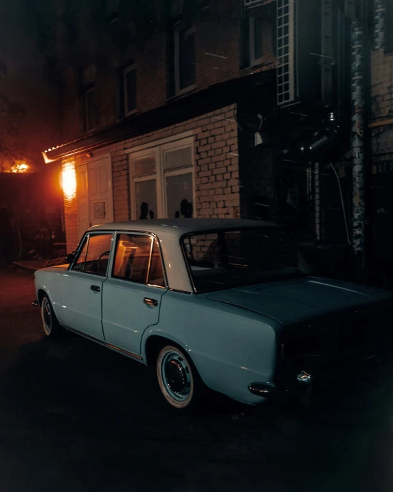 an old car parked next to a building at night