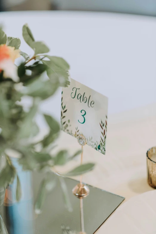 a small table number sits next to a vase with some flowers