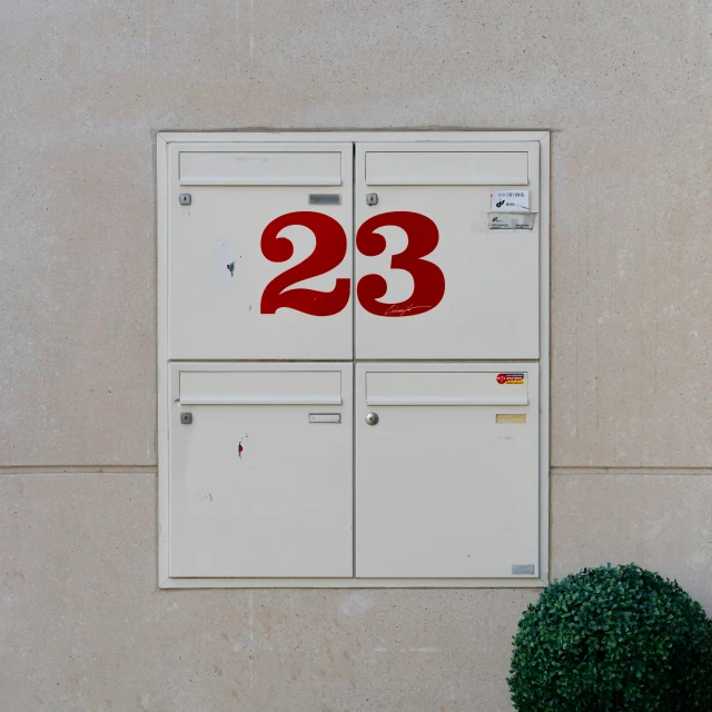 an outdoor mail box that is marked twenty three thirty three, and has been decorated in red with numbers