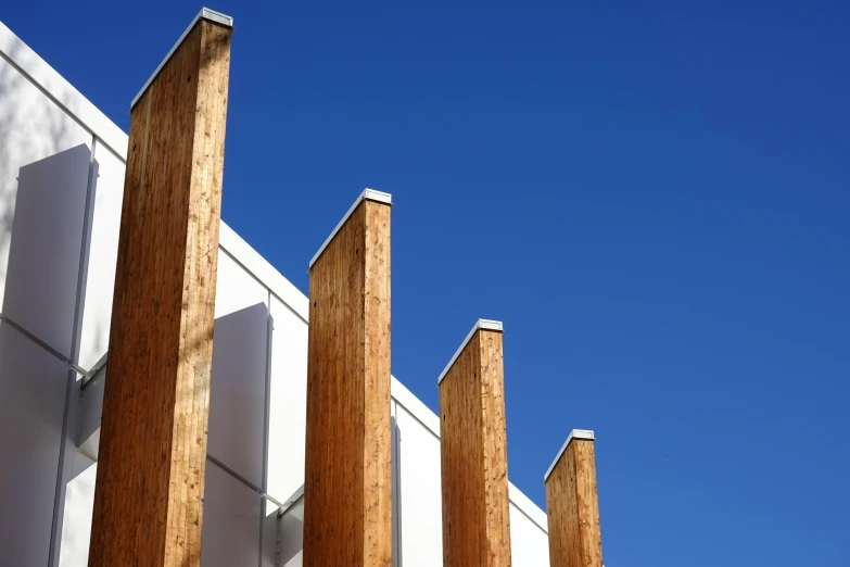 wood columns on wall in front of the clear blue sky