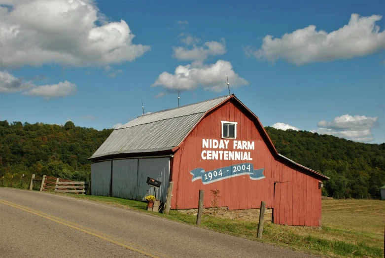 a red barn sits on the side of a country road