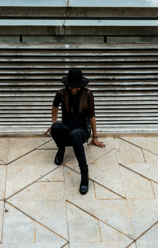 a woman with long hair sitting on a sidewalk