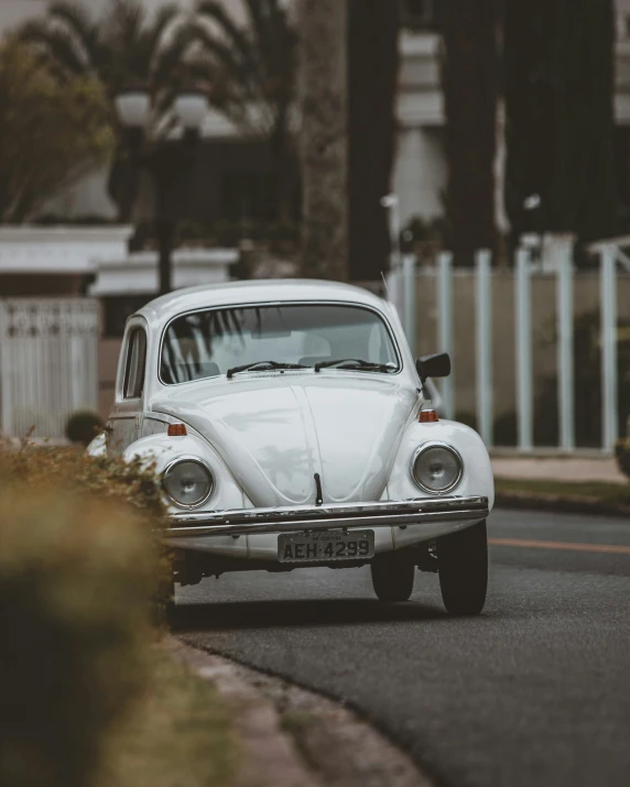 an old white volkswagen car driving down a street