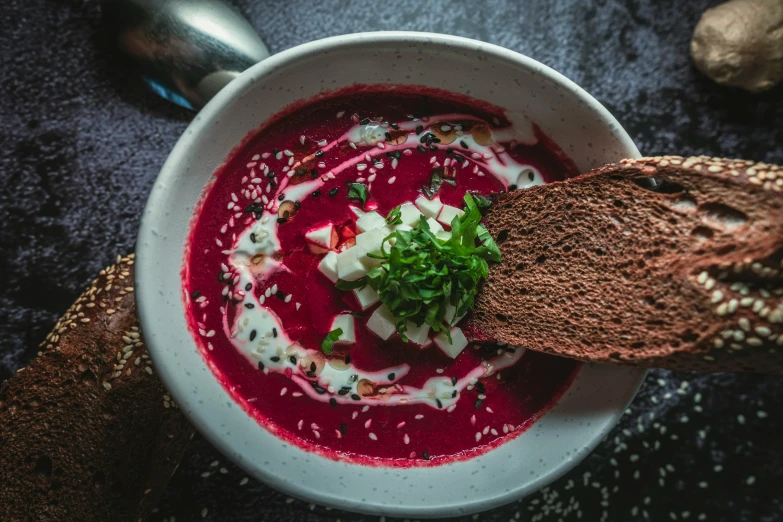 there is a bowl of red soup with bread