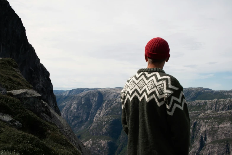 man standing on a cliff staring out over the valley