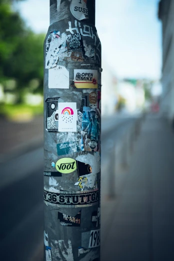 an odd sticker covered pole near the road