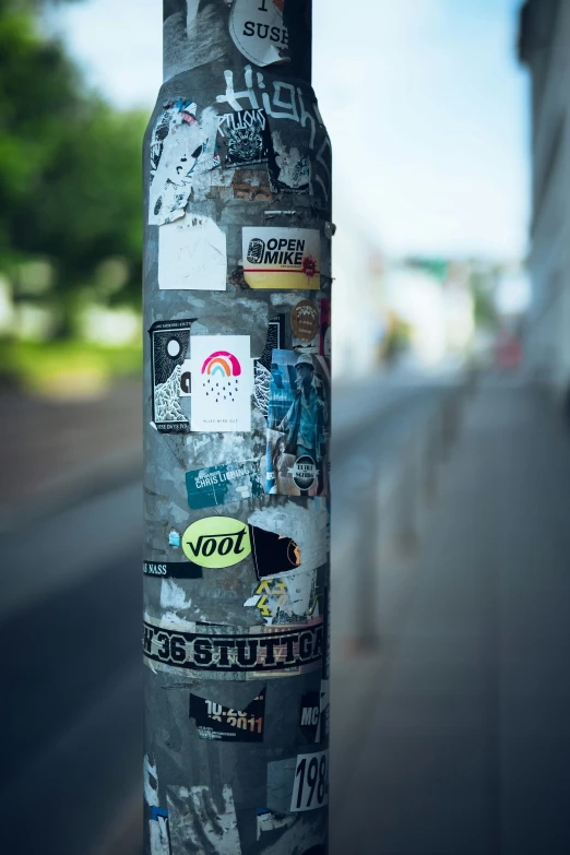 an odd sticker covered pole near the road