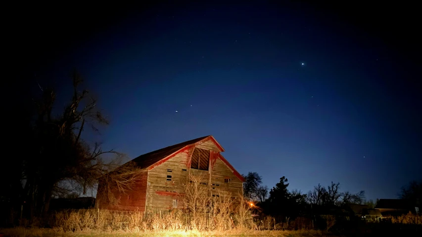 the barn is lit up at night and a bright light is shining