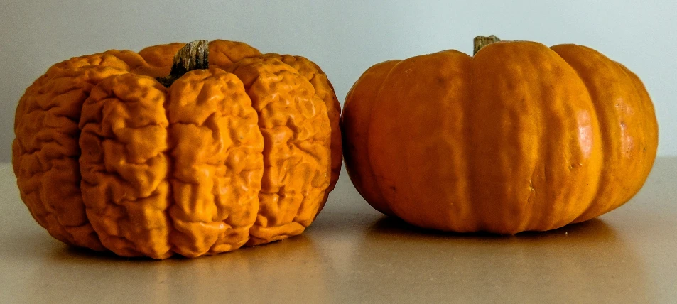 two pumpkins sitting next to each other on top of a table