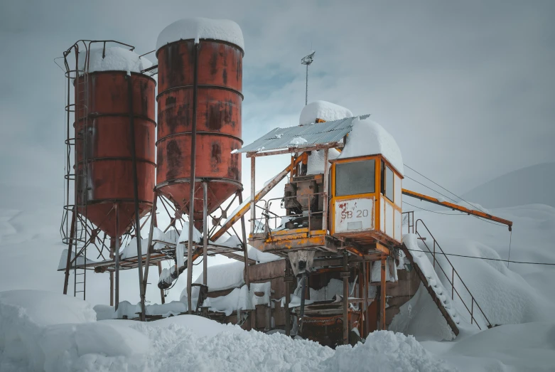 a snow covered field with red silos and two silo