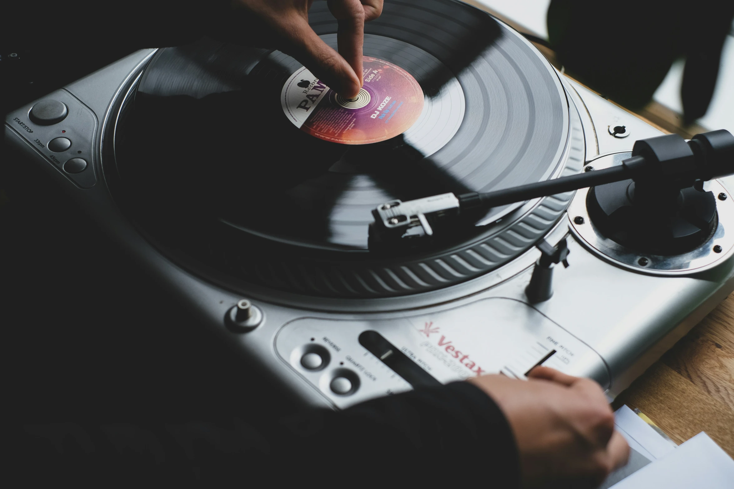 man using turntable with vinyl sleeve and record player