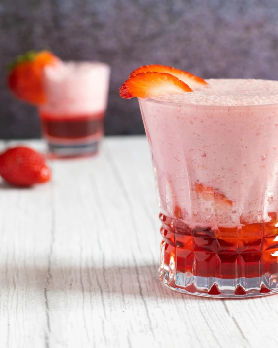 two ss of fruit shake, one with strawberries on the rim