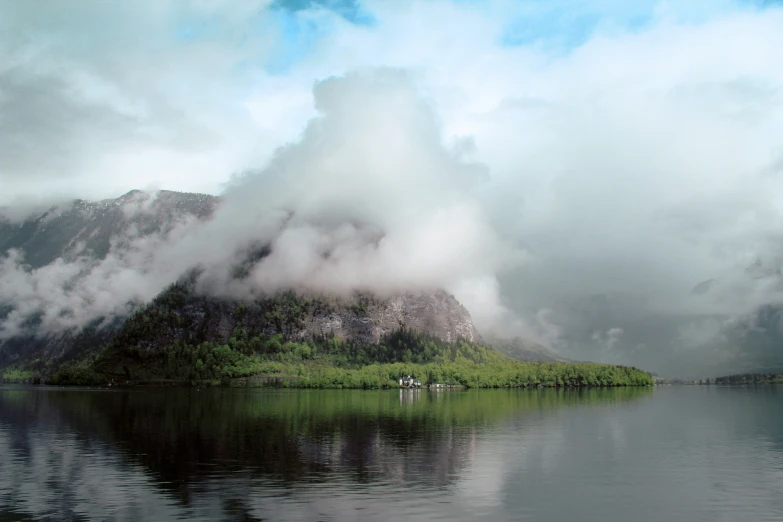 clouds roll in over mountains and a body of water