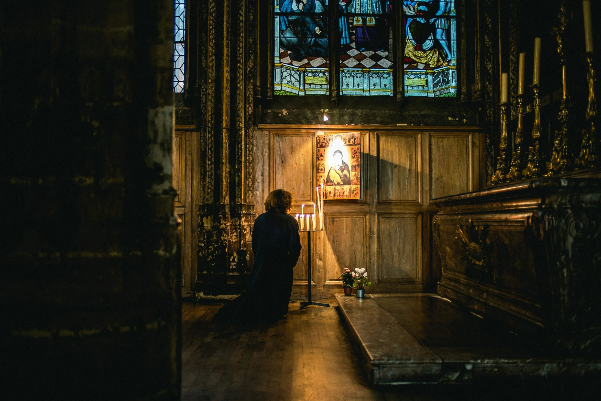 a person in the dark with stained glass in the background