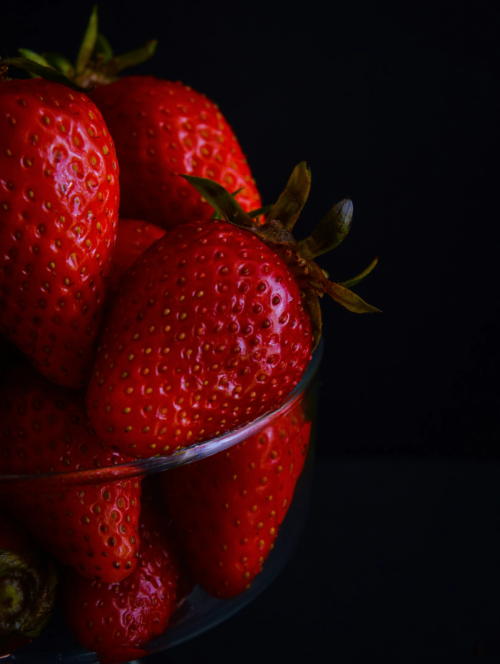 the big group of red strawberries are in a glass bowl