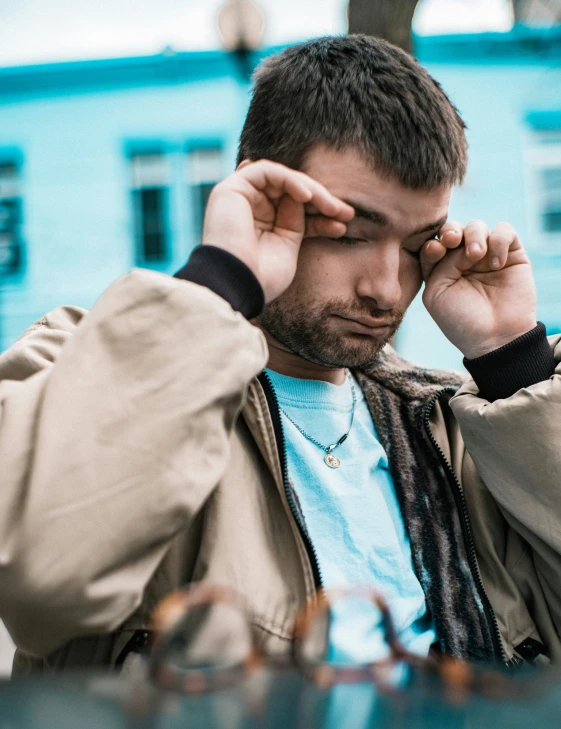 a man holds his hands to the forehead as he sits