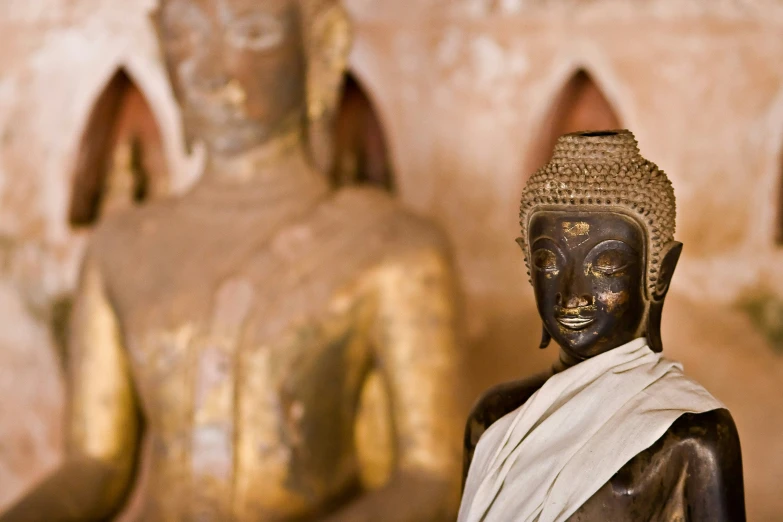 a black buddha statue sitting in front of gold statues