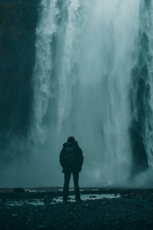 a person stands in front of a huge waterfall