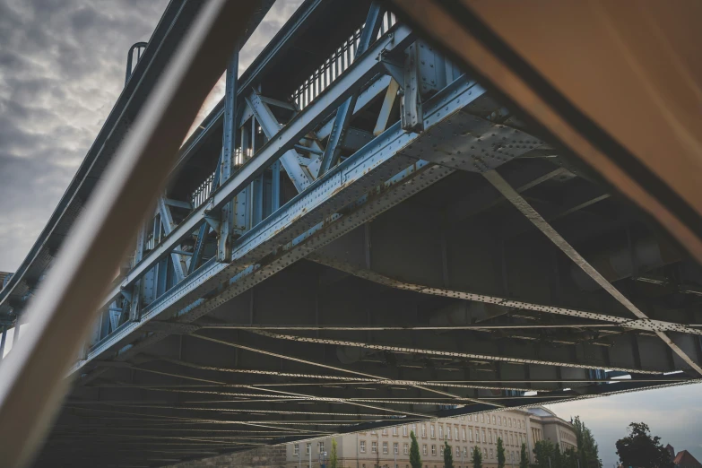 a very tall blue bridge spanning across a cloudy sky