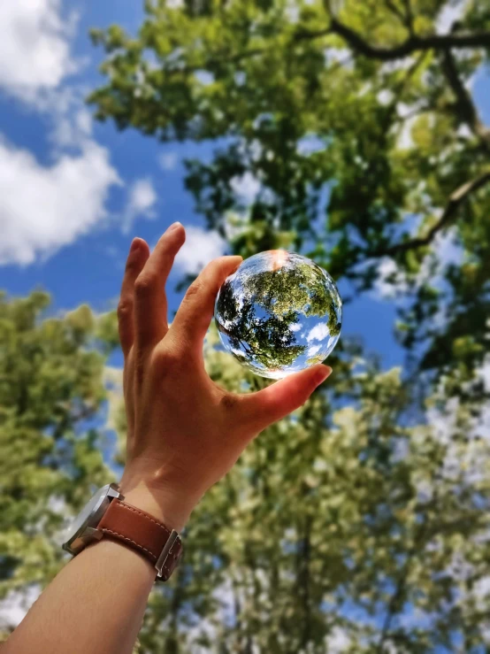 the ball is being held by a hand in front of the sky