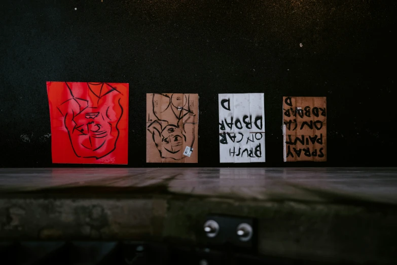 three wooden signs with faces are in front of a wall