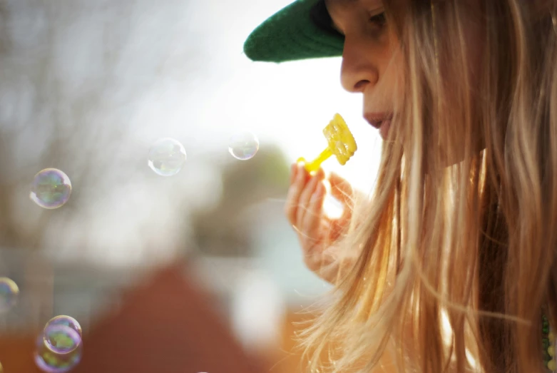 the blonde haired girl is blowing bubbles off her face