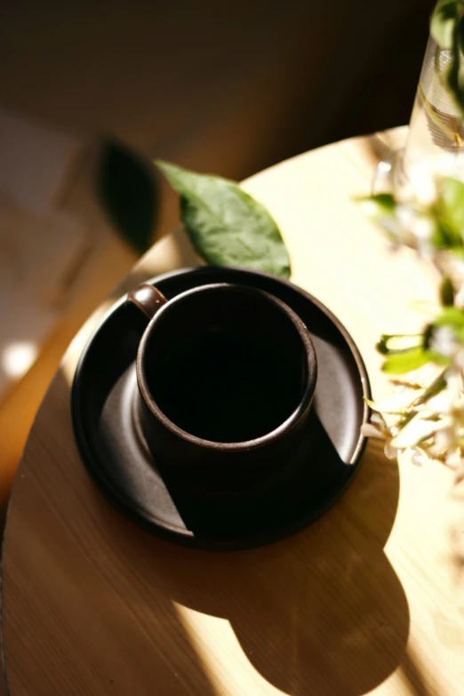 a cup sitting on top of a table near a vase