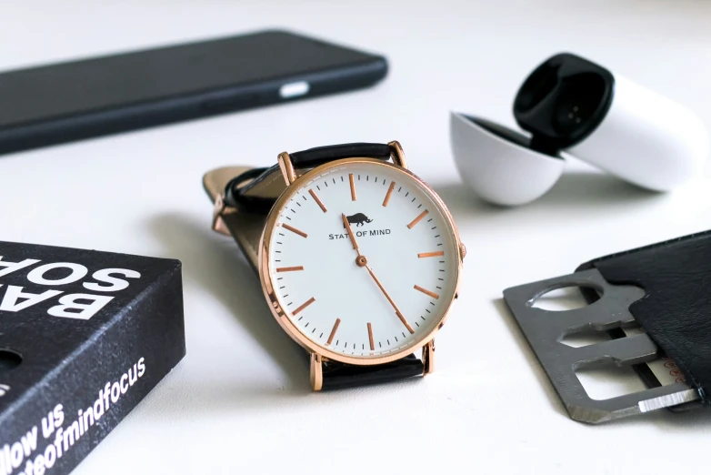 a watch sits next to a pair of glasses