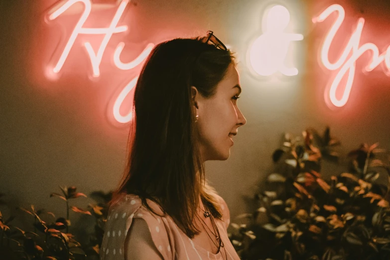 a woman looks to the side at an illuminated sign