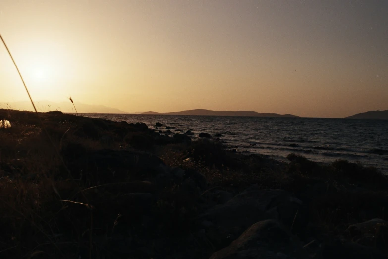 a bench sitting next to the ocean under a bright sun