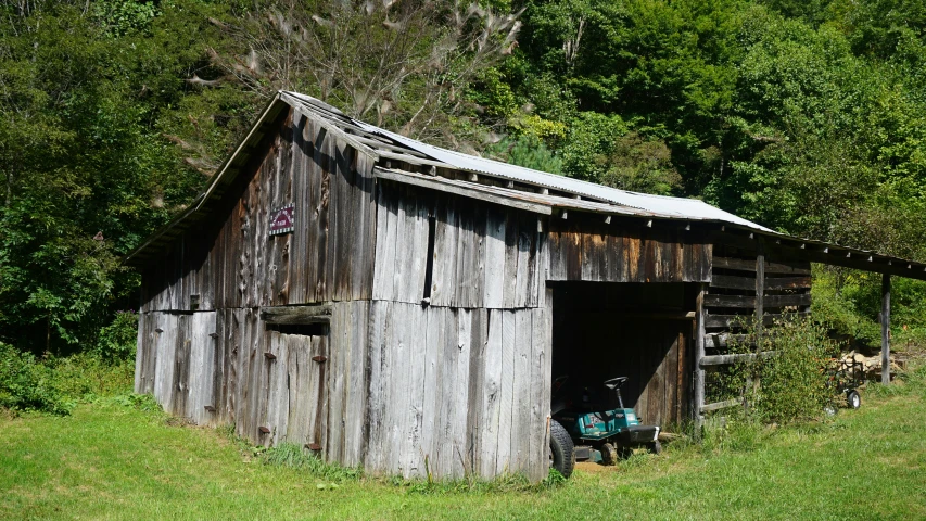 an old wooden outbuilding with a grass lawn chair in the doorway