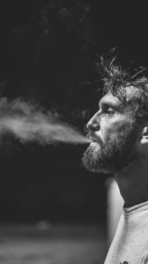 a man is smoking a cigarette while wearing a white shirt