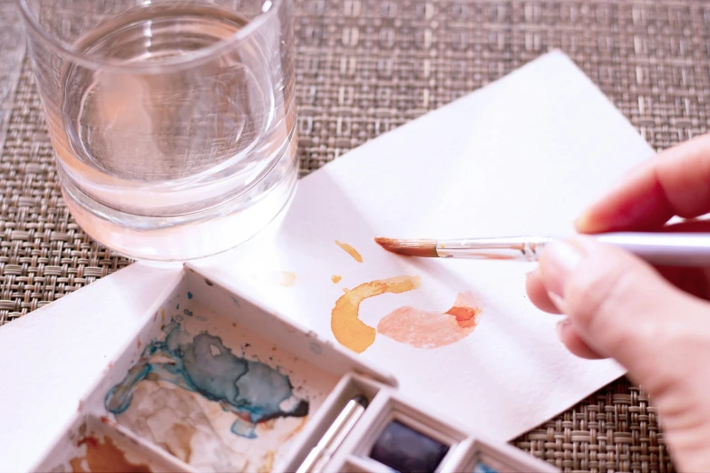 a hand using a brush to write with water on paper