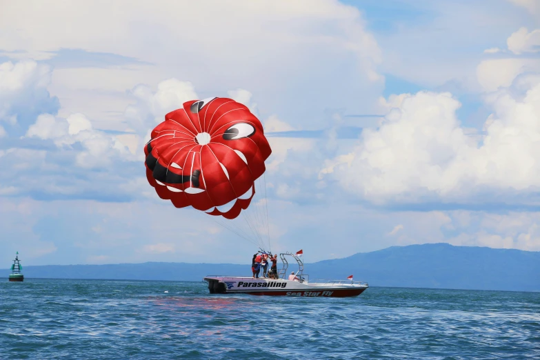 a man flying a large kite in the air over a boat