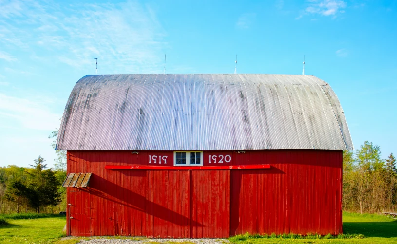 the large red barn is next to a wooded area