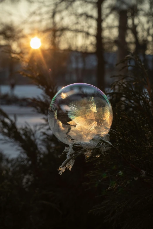 the sun is setting in a park with snow on it