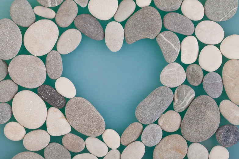 a heart made out of several rocks sitting on top of a blue background