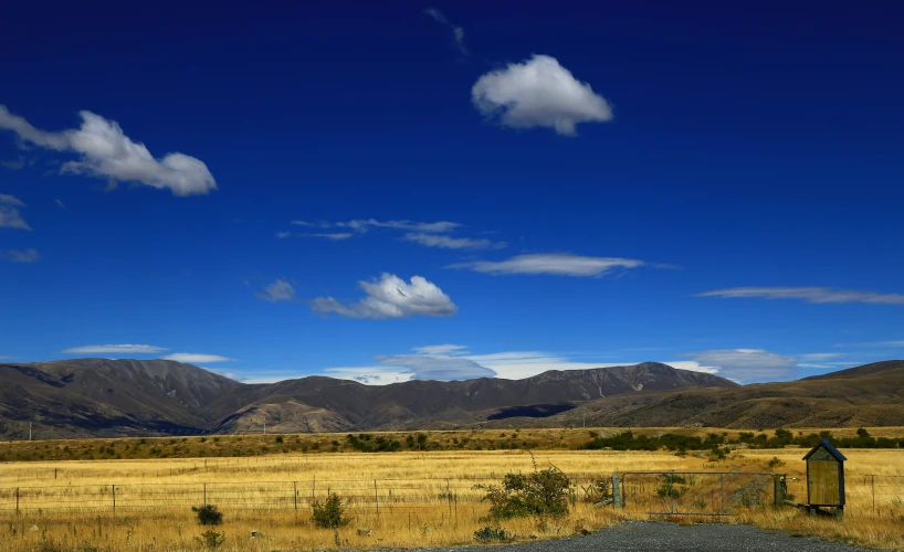 a farm with mountains and grass in the background