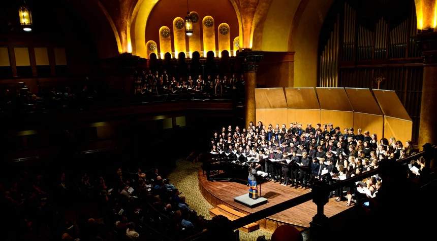 a choir performing on stage in front of a concert audience