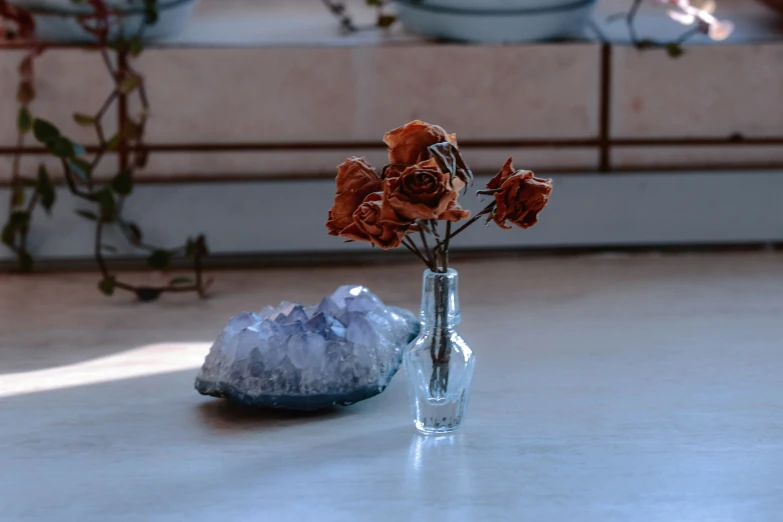 three roses in a vase and a rock