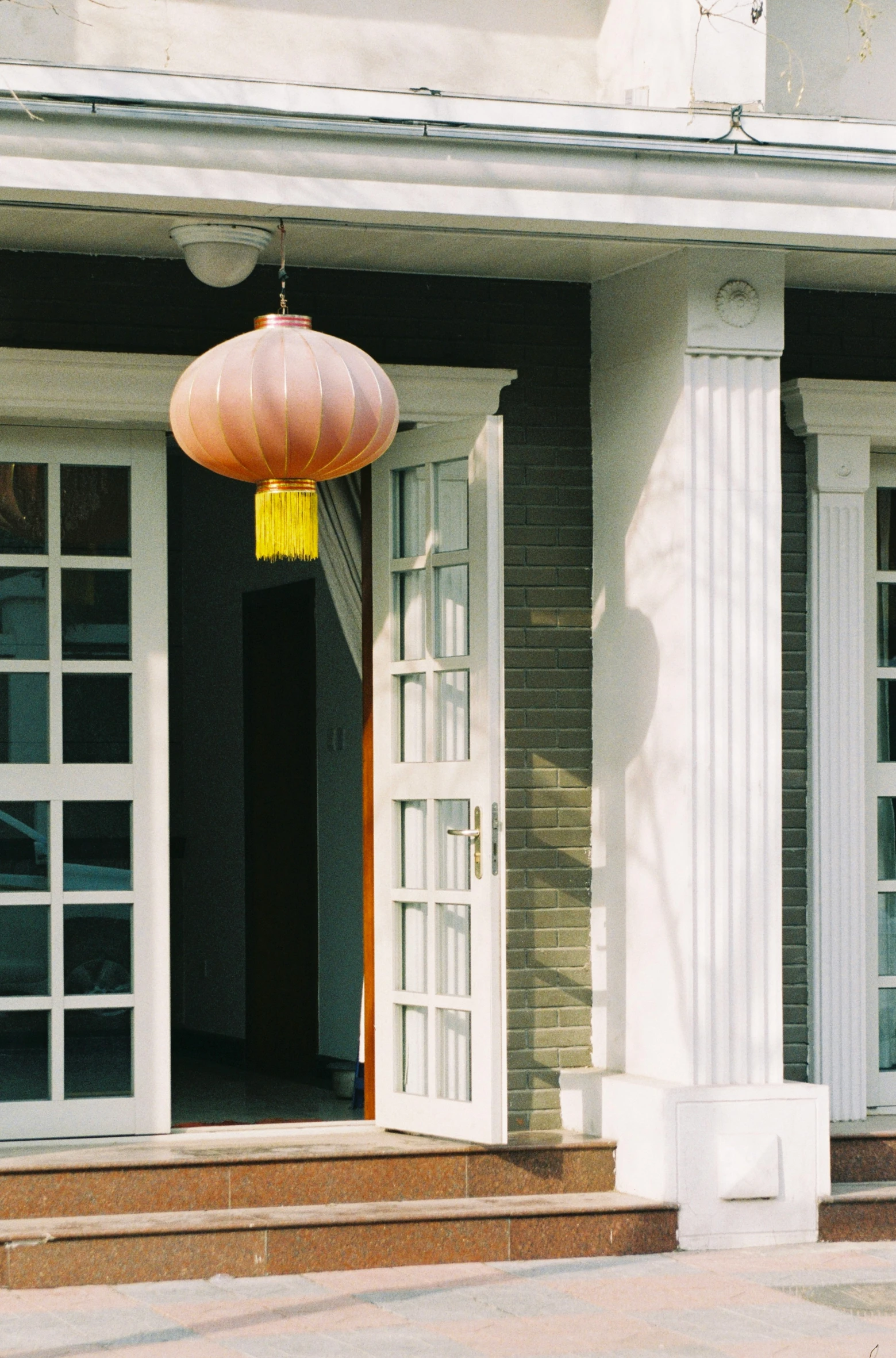 a yellow lantern hangs from the door on the front porch of a house