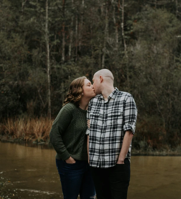 an engaged couple kisses while standing in the water