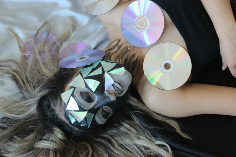 a woman that has her face painted with cds on her face